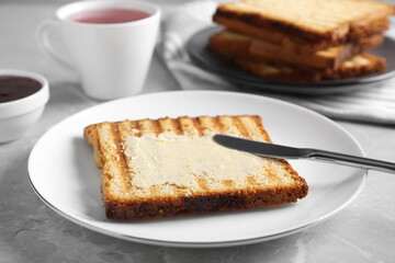 Tasty toast with butter served on grey marble table, closeup
