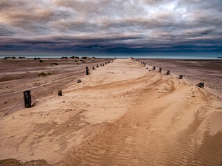 Dramatic scenery with wooden stakes under a dark sky leading the path towards the ocean