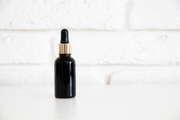 Essence oil in black bottle on white background. Aroma oil bottle mockup. Cosmetic for face.