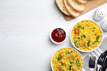 Delicious rice pilaf with meat served on white wooden table, flat lay. Space for text