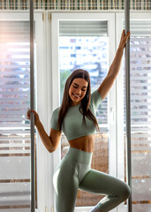 Fototapeta premium Shot of a powerful female in green sportswear standing at home and posing. Attractive young adult in sportswear. Portrait of a sporty young woman taking a break and posing while exercising. Copy space