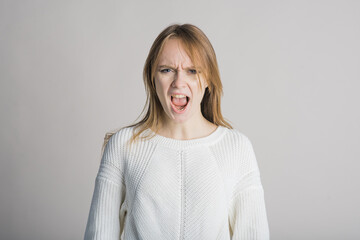 Portrait of a beautiful girl on a white background in the studio who is angry and screams