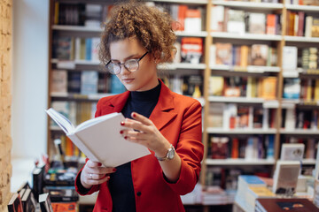 Young woman reading book. Young female student reading book at book store.