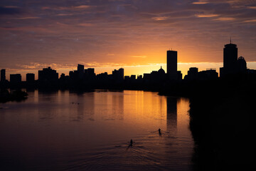 Fototapeta na wymiar Two rowers on the charles river in Boston during an orange sunrise