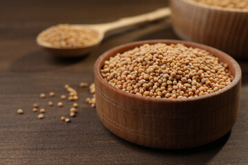Mustard seeds in wooden bowl on table, closeup. Space for text