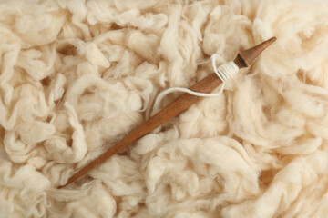 Soft white wool with spindle as background, top view © New Africa