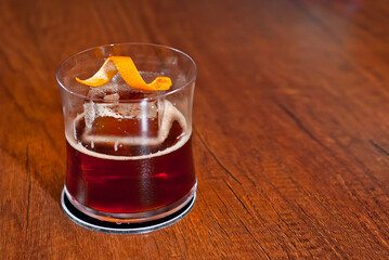 Yellow cocktail on bar counter. Whiskey, rum or brandy on a background of bar interior. Glass with booze on a wooden board. Copy space and free space for text near the glass.