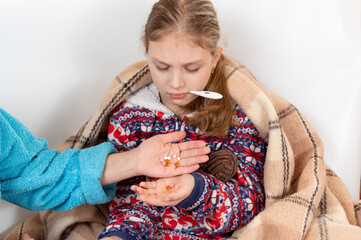 Mom gives the child many pills. Mom treats the child. A child with a thermometer in his mouth.