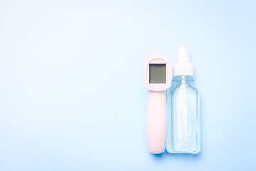 infrared thermometer and antiseptic on a blue background . antiseptic. treatment of hands. prevention. non-contact temperature measurement. health. coronavirus. pandemic. human health. check the tempe