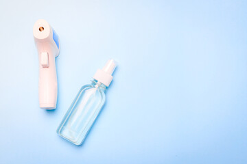 infrared thermometer and antiseptic on a blue background . antiseptic. treatment of hands. prevention. non-contact temperature measurement. health. coronavirus. pandemic. human health. check the tempe