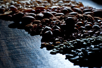 Obraz premium Many kinds of nuts close up. Heap of nuts on a black wooden board. Nuts are stacked on the table. Contrasting dramatic light as an artistic effect.