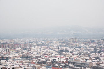 Fototapeta na wymiar High angle view of snow covered cityscape of Pirot, Serbia, on a misty, cloudy, murky winter day