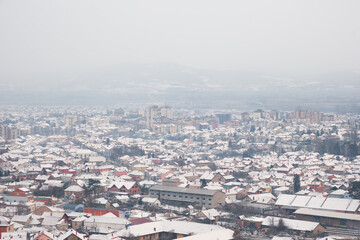 Obraz premium High angle view of snow covered cityscape of Pirot, Serbia, on a misty, cloudy, murky winter day