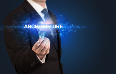 Obraz premium Businessman holding light bulb with ARCHITECTURE inscription, innovative technology concept