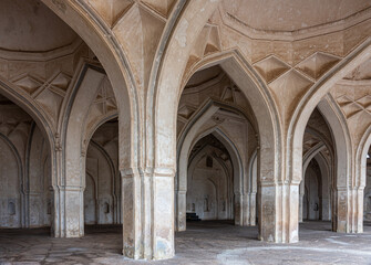 Vijayapura, Karnataka, India - November 8, 2013: Vaulted beige brown vaulted hall and pillars of Ibrahim Rauza mosque.