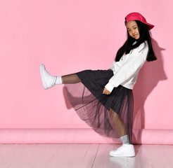 Side view of a fashionable portrait of a little Korean girl model posing in the studio on a pink...