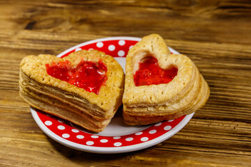 Heart shaped puff cookies with jam on a wooden table. Dessert on Valentine`s Day