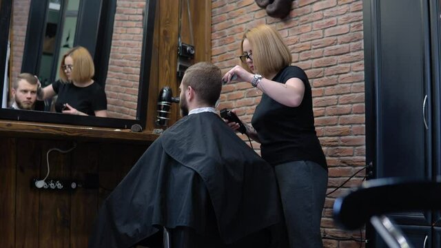 The client's hair is cut with a trimmer in a barbershop