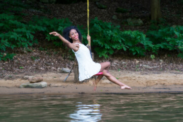 Woman  at lake on swing, large boulder, and in water