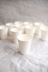 Fototapeta na wymiar disposable cups made of white paper are laid out on gray crumpled paper