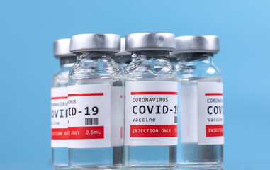 Glass vials of the covid-19 vaccine against blue background
