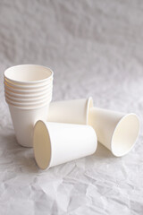 disposable cups made of white paper are laid out on gray crumpled paper