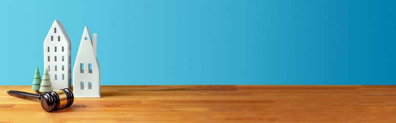 Richterhammer, Häuser und Bäume auf Tisch vor blauem Hintergrund. Anwaltskanzlei