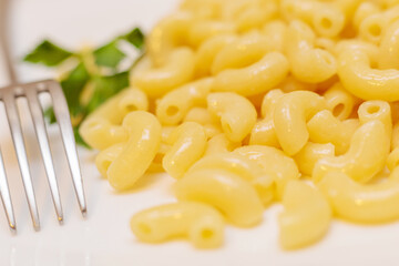 Boiled yellow pasta on a white plate with a fork