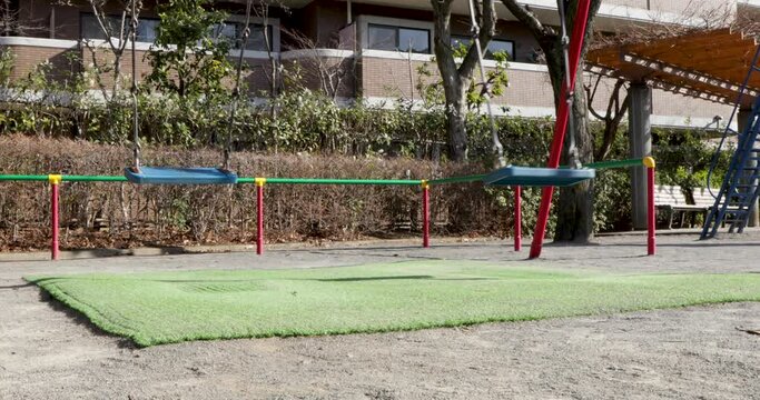 誰もいない小さな公園で揺れるブランコ