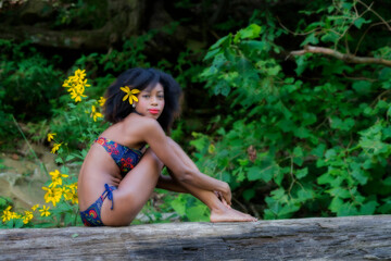 Obraz premium Model in nature posing on log with flowers