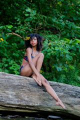 Model in nature posing on log with flowers