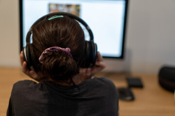 child on computer from behind with headphones on doing her homework
