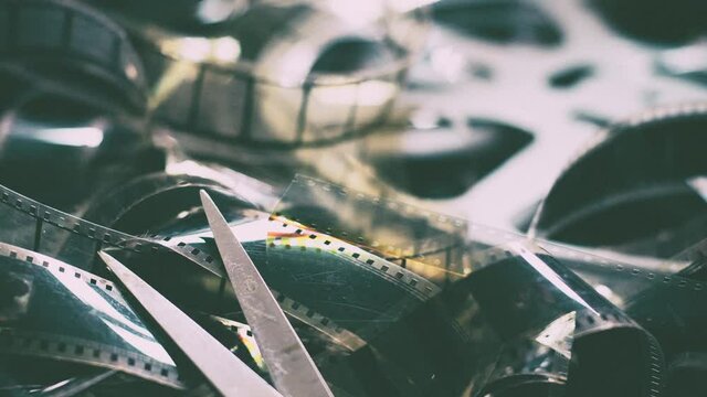 Movie background concept panning on unrolled camera film and scissors, editing and final cut