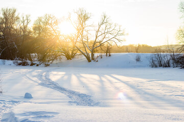 Sunny winter landscape on a sunny day. Trail on the frozen river