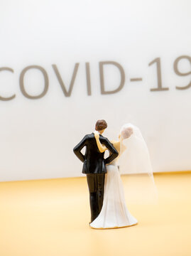 Wedding Couple Standing In Front Of A Large Lettering With Covid 19 And Celebrating Alone Without Party Guests