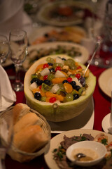 Served festive table. In the center of the table is a fruit salad in a melon.