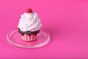 Creative minimal concept made of cupcake with colorful sugar decoration on a glass plate on pink  background.