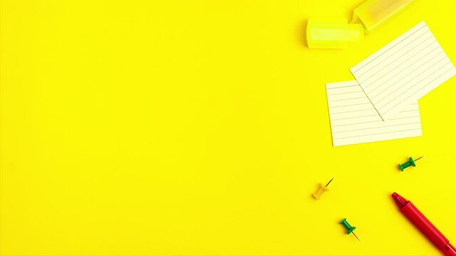 Stop motion animation of pen, notepad, marker, push pins, paper clip pencils on yellow background. Flat lay top view. Education template back to school and online study concept with copy space