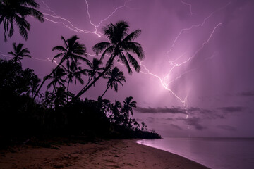 Dramatic Lightning strikes the ocean from a palm beach