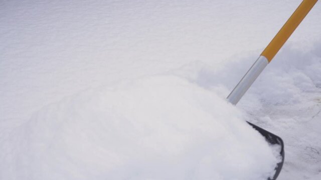 Clearing snow drifts on the sidewalk with a snow shovel close-up.