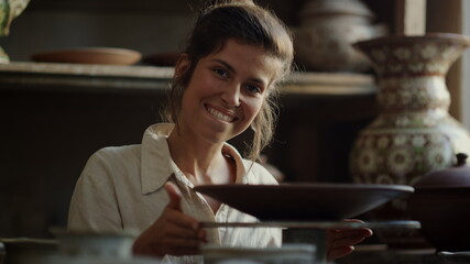 Excited artist playing with wheel in pottery. Woman spinning potters wheel 