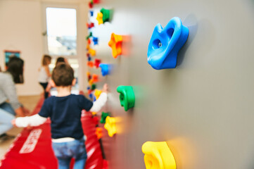 Wall with climbing grips in daycare or kindergarten, activity for little children - obrazy, fototapety, plakaty