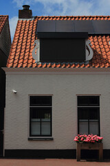 View of a residential house with two windows and flowers, blue sky in the background
