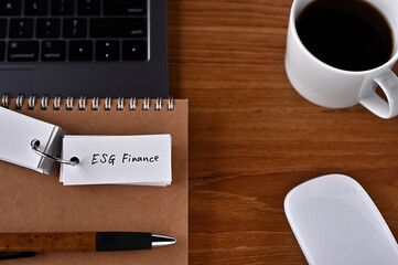 There's a cup of coffee, a laptop and a notebook with a word book on it that says ESG Finance.