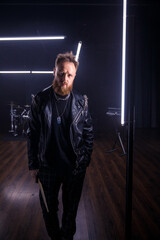 brutal portrait of a man musician with a beard and in black clothes on the background of musical...