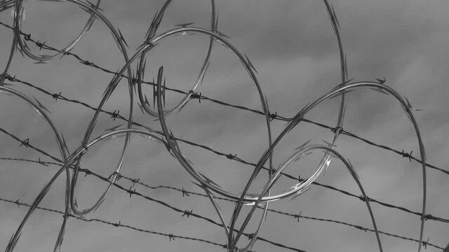Razor wire with cloudy background. Black and white.
