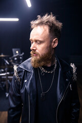 brutal portrait of a man musician with a beard and in black clothes on the background of musical...