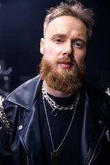brutal portrait of a man musician with a beard and in black clothes on the background of musical...