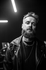 brutal portrait of a man musician with a beard and in black clothes on the background of musical...