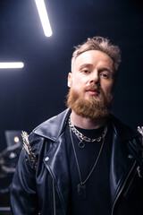 brutal portrait of a man musician with a beard and in black clothes on the background of musical...